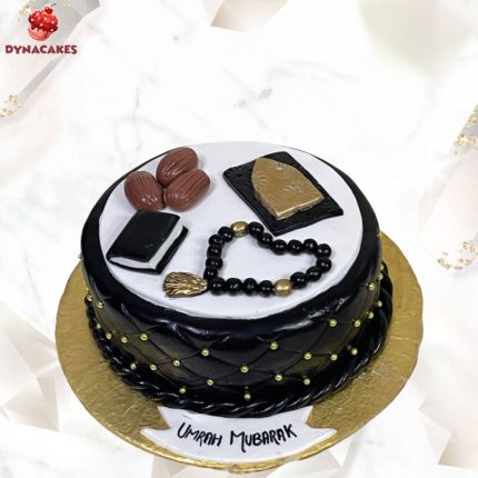 Umrah Mubarak theme cake with black and white design featuring tasbih, dates, and Islamic books in Karachi.