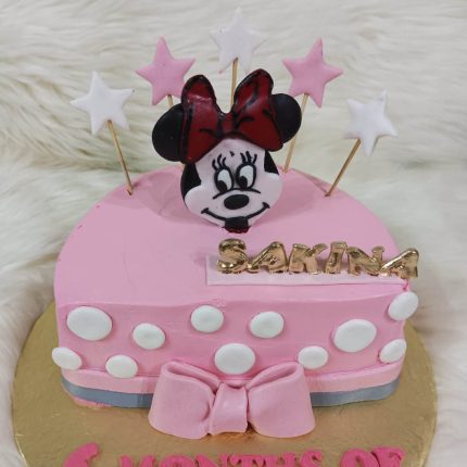 Pink Minnie Mouse-themed birthday cake with polka dots, stars, and a personalized name topper for Sakina