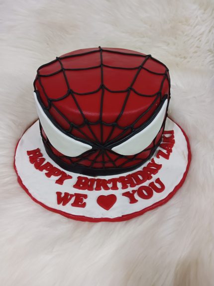 A Spider-Man-themed birthday cake designed to look like Spider-Man's mask with the message 'Happy Birthday Zaki, We Love You' written at the base