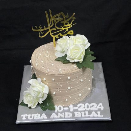 Elegant beige wedding cake with white roses and Arabic calligraphy topper, personalized for Tuba and Bilal on 10-1-2024