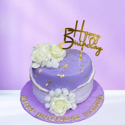 Purple color cream birthday cake with white floral decorations and golden accents, perfect for birthdays in Karachi.